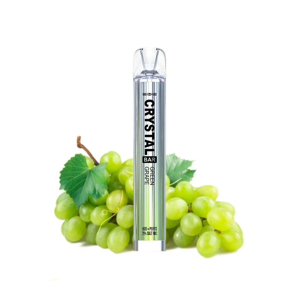 Vaper SKE Crystal Bar Green Grape vertical, con cuerpo estriado y boquilla transparente, delante de racimos de uvas verdes.