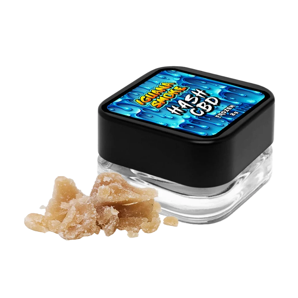 Tarro de Hash Frozen Golden Cider de Iguana Smoke con tapa negra y etiqueta azul, junto a fragmentos beige sobre fondo negro.