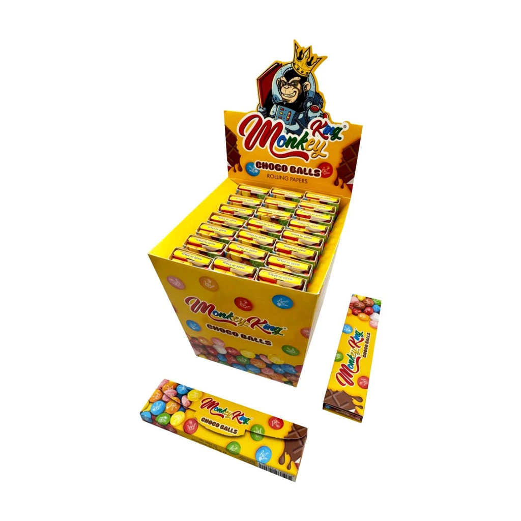 Expositor amarillo de papel Monkey King Choco Balls con varios libritos y dos paquetes delante, decorados con dulces de colores.