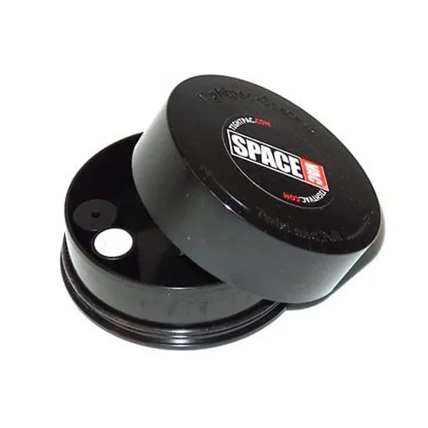 Recipiente negro Spacevac Tightpac entreabierto, con tapa circular inclinada y dos piezas redondas visibles en el interior.