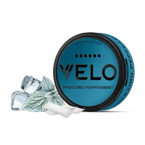 Lata circular azul de VELO Freezing Peppermint con bolsitas blancas, hojas escarchadas y cubitos de hielo sobre fondo negro.
