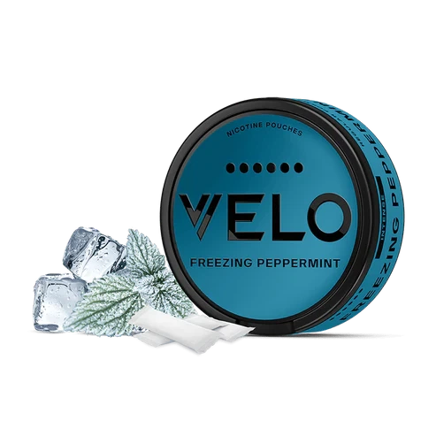 Lata circular azul de VELO Freezing Peppermint con bolsitas blancas, hojas escarchadas y cubitos de hielo sobre fondo negro.