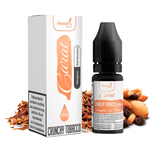 Frasco y caja de Omerta Carat Salts Crunchy Tobacco, con etiqueta de 10 ml y 10 mg/ml, junto a tabaco y frutos secos.