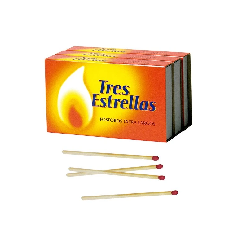 Cajas de fósforos Tres Estrellas en amarillo y rojo, con dibujo de una llama y varios fósforos extralargos de madera con cabeza roja.