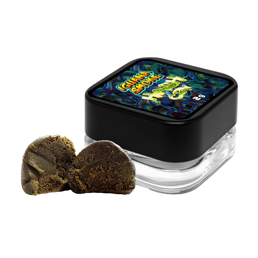 Tarro de Hash CBN de Iguana Smoke con tapa negra y etiqueta multicolor, junto a dos fragmentos marrones sobre fondo negro.