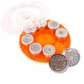 Estuche circular naranja STORZ & BICKEL abierto, con tapa transparente y cápsulas perforadas; una cápsula abierta aparece delante.