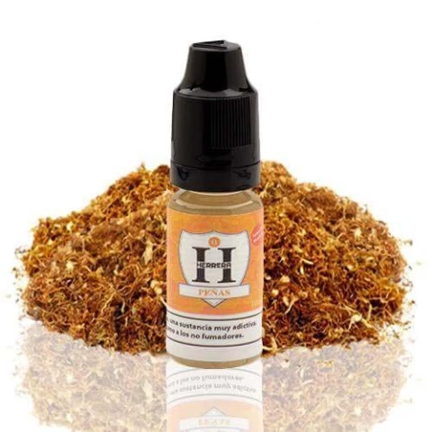 Frasco Herrera Salts Peñas con tapón negro y etiqueta naranja, delante de un montón de tabaco sobre fondo blanco.