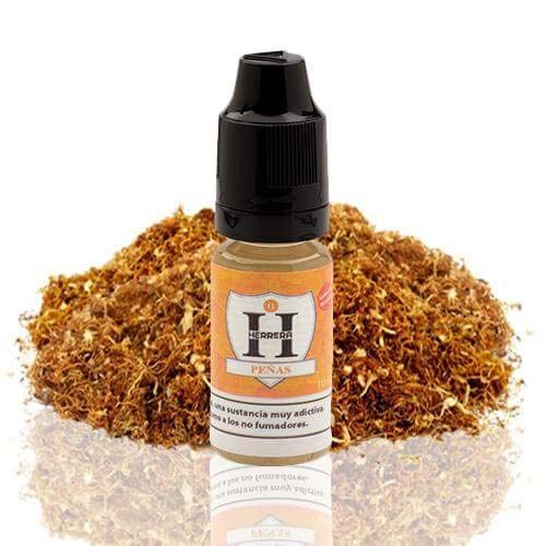 Frasco Herrera Salts Peñas con tapón negro y etiqueta naranja, delante de un montón de tabaco sobre fondo blanco.