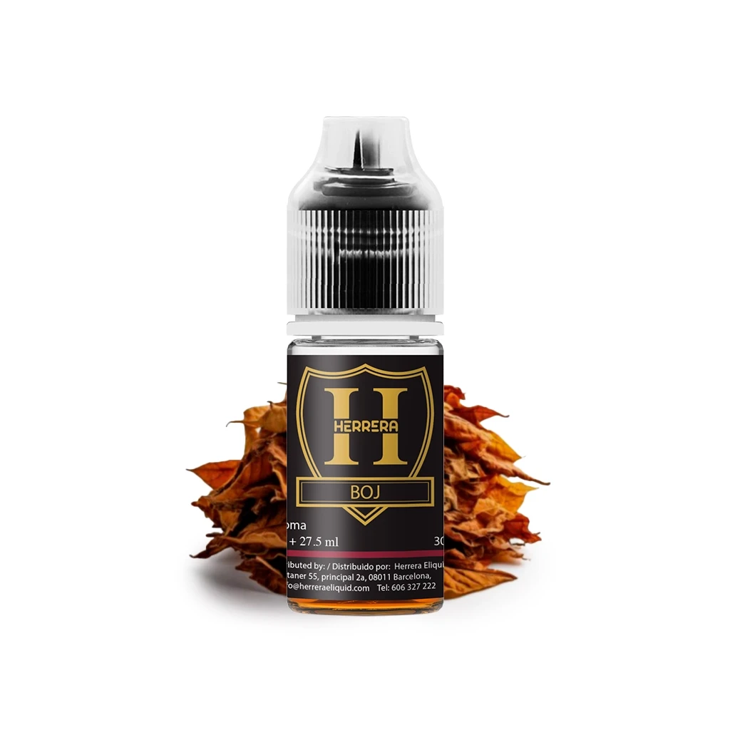 Frasco Herrera Boj Longfill con tapón estriado y etiqueta negra y dorada, delante de un montón de hojas secas marrones.