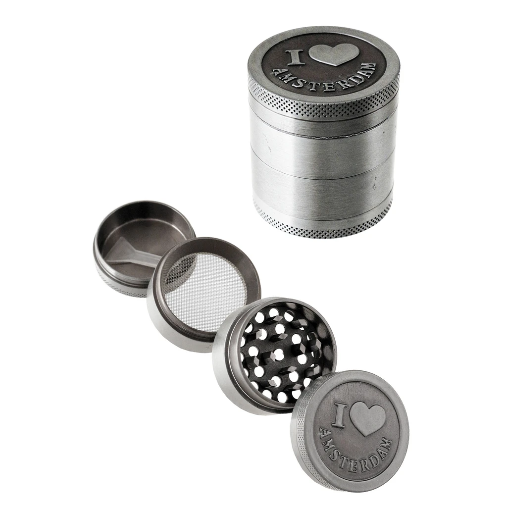 Grinder metálico gris I Amsterdam, cerrado y desmontado, con dientes, tamiz y pequeña espátula sobre fondo blanco.