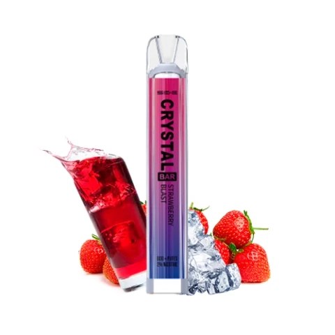 Vaper SKE Crystal Bar Strawberry Blast con cuerpo rosa y violeta y boquilla transparente, junto a fresas, hielo y un vaso de bebida roja.