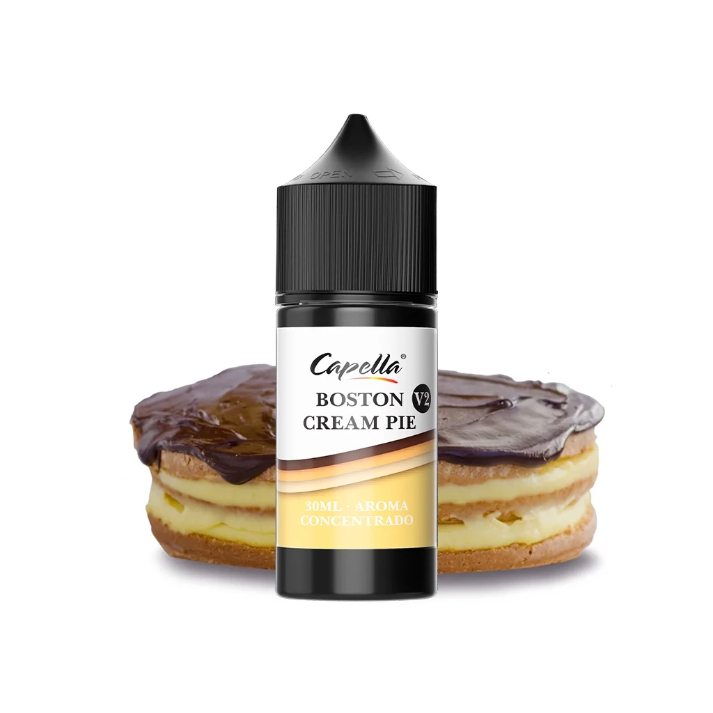 Bote Capella Boston Cream Pie V2 de 30 ml con tapón negro, delante de un pastel con capas de crema y cobertura de chocolate.