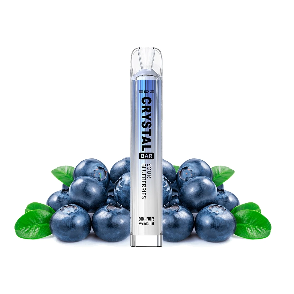 Vaper SKE Crystal Bar Sour Blueberries con cuerpo plateado y azul y boquilla transparente, rodeado de arándanos y hojas verdes.