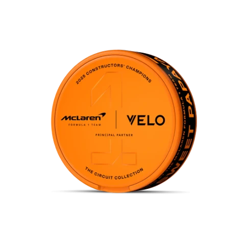 Lata circular naranja de VELO Sweet Papaya sobre fondo negro, vista en perspectiva, con logotipos de McLaren y VELO y un gran número 1 en relieve.