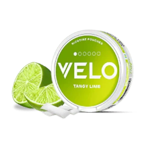 Envase redondo VELO Tangy Lime con etiqueta verde, junto a lima cortada y bolsitas blancas sobre fondo negro.