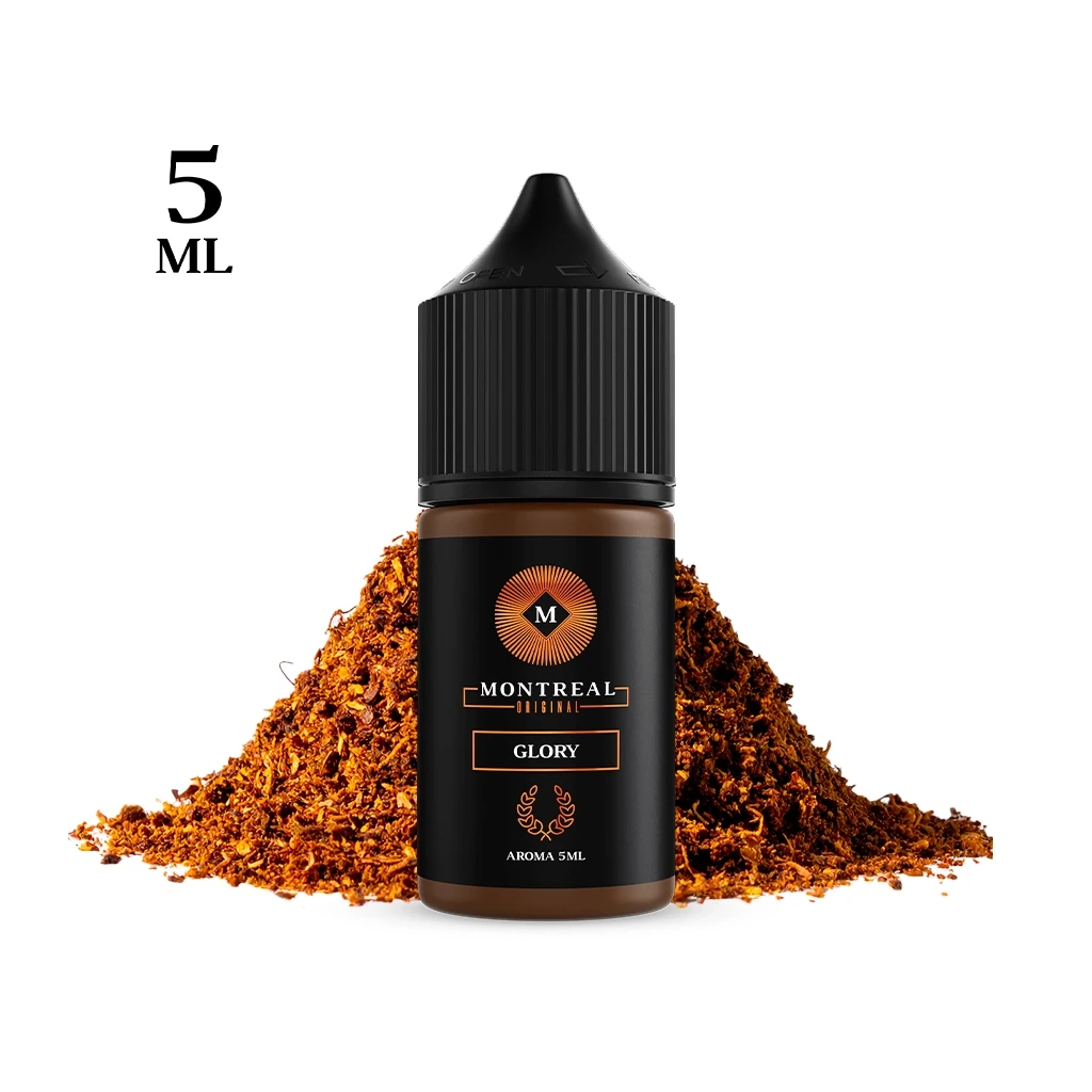 Frasco Montreal Original Glory de 5 ml con tapón negro y etiqueta negra y dorada, ante un montón de hebras marrones.