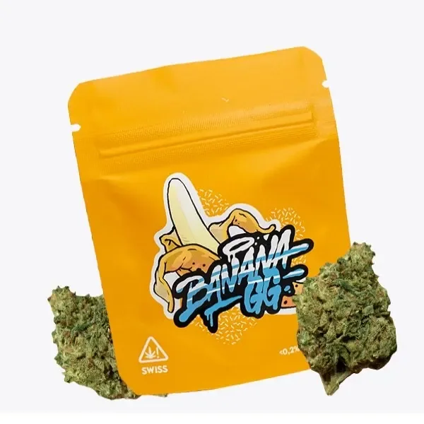 Bolsa amarilla de Banana GG con dibujo de un plátano y logotipo central, flanqueada por cogollos verdes sobre fondo claro.