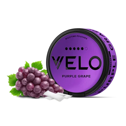Envase redondo violeta de VELO Purple Grape con un racimo de uvas y bolsas blancas delante, sobre fondo negro. Envase redondo violeta de VELO Purple Grape con un racimo de uvas y bolsas blancas delante, sobre fondo negro.