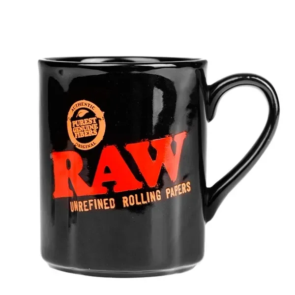Taza negra brillante con asa a la derecha, gran logotipo RAW rojo y texto «Unrefined Rolling Papers» en tono dorado.