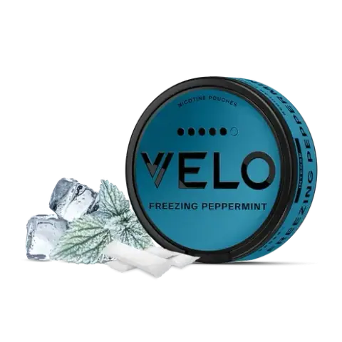 Envase redondo turquesa de VELO Freezing Peppermint junto a bolsas blancas, hojas de menta y cubitos de hielo sobre fondo negro.