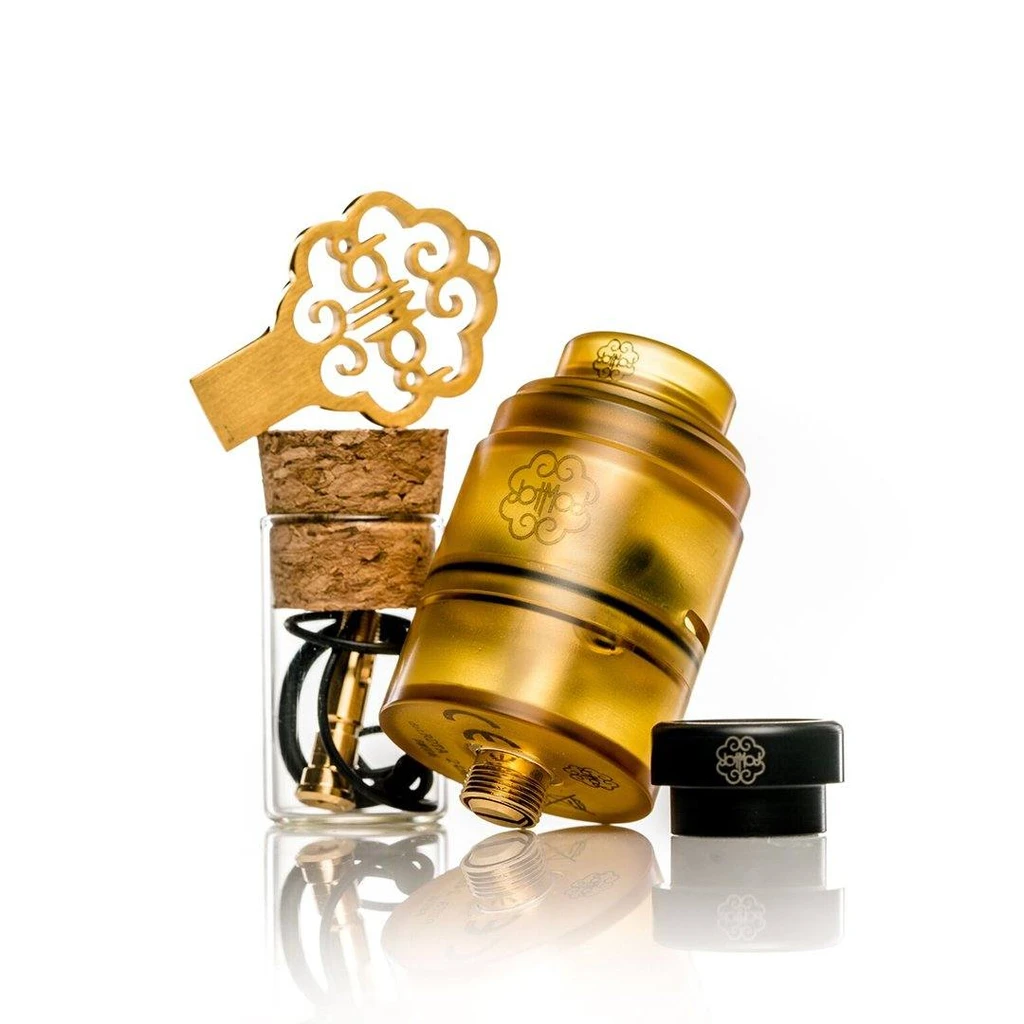 Atomizador DOTMOD DOTRDTA dorado e inclinado, junto a una boquilla negra, un frasco con piezas y una herramienta dorada calada.