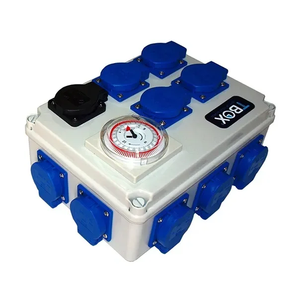 Temporizador TBOX en caja gris, con dial circular y varias tomas con tapas azules y una negra, visto en perspectiva sobre fondo blanco.