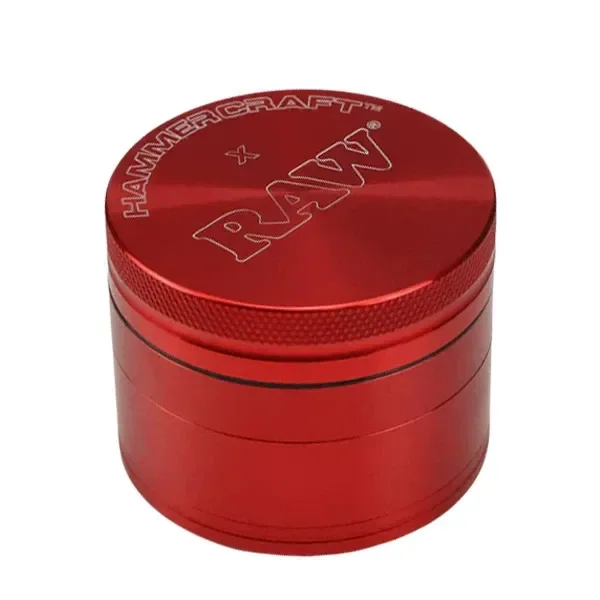 Grinder rojo cilíndrico cerrado, con borde moleteado y los nombres Hammercraft y RAW grabados en la tapa, sobre fondo blanco.