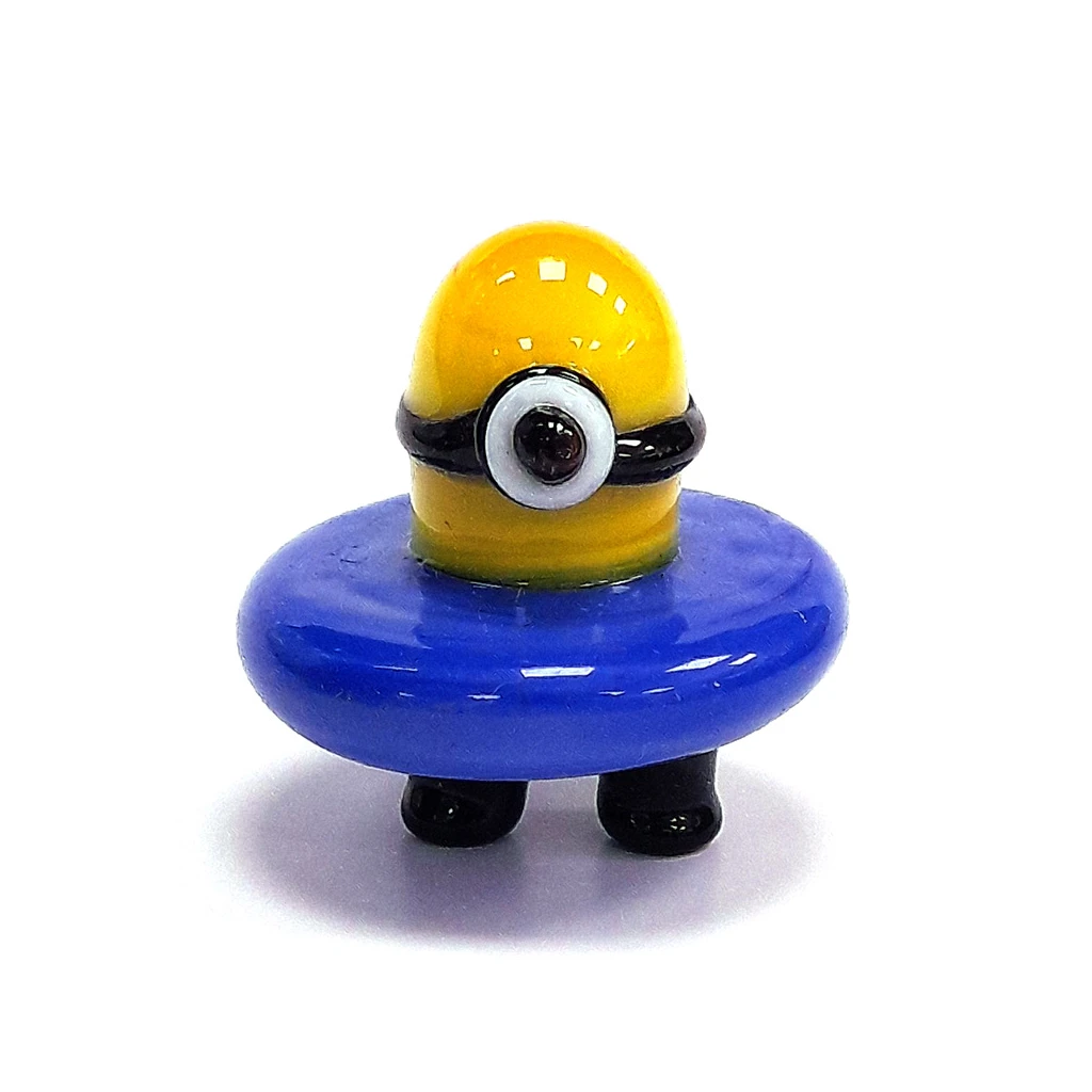 Carb cup con figura de Minion amarillo, un ojo con gafas, aro azul ancho alrededor del cuerpo y pies negros sobre fondo blanco.