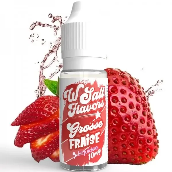Frasco de e-líquido Wsalt con tapón blanco y etiqueta roja «Grosse Fraise», rodeado de fresas y una salpicadura de líquido.