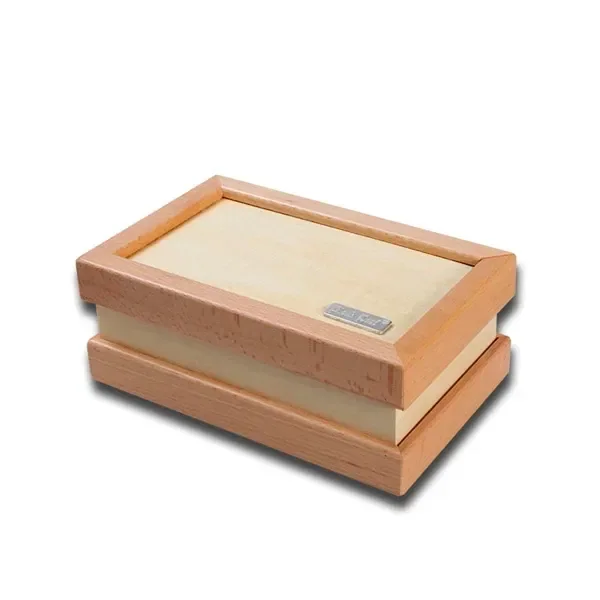 Caja de curación rectangular cerrada, con marco de madera clara, panel central pálido y pequeña placa metálica en la tapa.