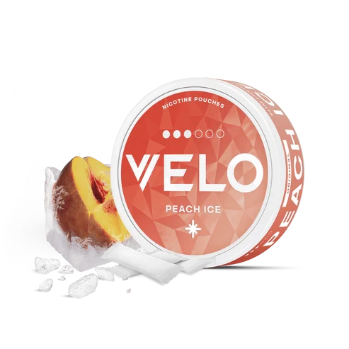 Lata redonda VELO Peach Ice con etiqueta coral, junto a un trozo de melocotón, hielo y bolsas blancas sobre fondo negro. Lata redonda VELO Peach Ice con etiqueta coral, junto a un trozo de melocotón, hielo y bolsas blancas sobre fondo negro.
