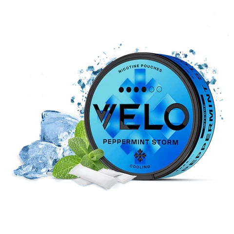 Envase circular azul de VELO Peppermint Storm con bolsas blancas, hojas de menta y cubitos de hielo sobre fondo negro.