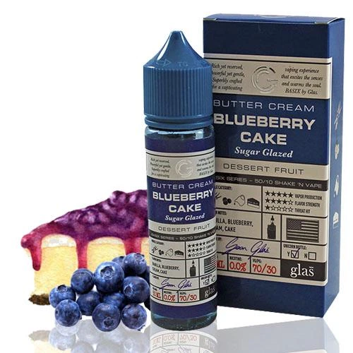 Frasco y caja azul de Glas Blueberry Cake, con una porción de tarta cubierta de glaseado morado y arándanos sobre fondo blanco.
