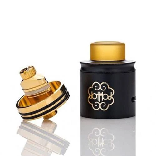 Atomizador DOTMOD DOTRDA24 Gold con cuerpo negro, boquilla dorada y base desmontada al lado, sobre una superficie reflectante.