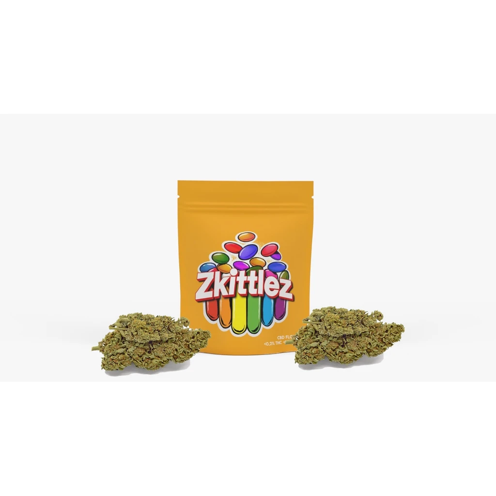 Bolsa amarilla de Zkittlez con logotipo multicolor y cogollos verdes dispuestos delante sobre fondo blanco.