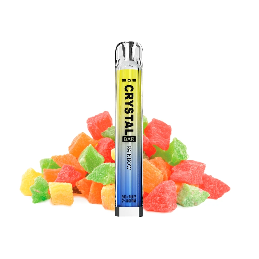 Vaper SKE Crystal Bar Rainbow en vertical, con cuerpo amarillo y azul y boquilla transparente, delante de golosinas de colores. Vaper SKE Crystal Bar Rainbow en vertical, con cuerpo amarillo y azul y boquilla transparente, delante de golosinas de colores.