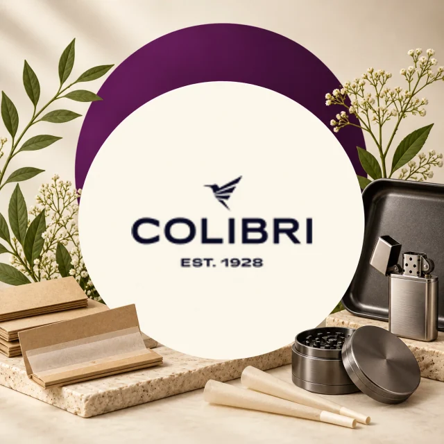 Logotipo de Colibri con el texto «Est. 1928», junto a un mechero abierto, un grinder, papel de liar y conos sobre una base clara. Logotipo de Colibri con el texto «Est. 1928», junto a un mechero abierto, un grinder, papel de liar y conos sobre una base clara.
