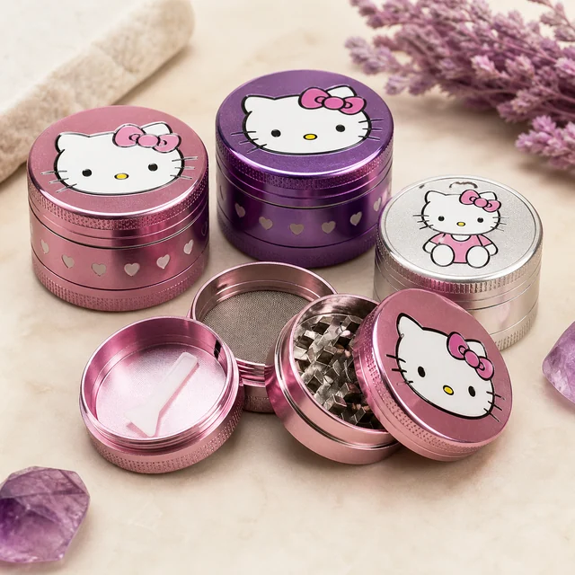 Grinders de Hello Kitty en rosa, morado y plateado, con uno rosa desmontado que muestra dientes, tamiz y una pequeña espátula. Grinders de Hello Kitty en rosa, morado y plateado, con uno rosa desmontado que muestra dientes, tamiz y una pequeña espátula.