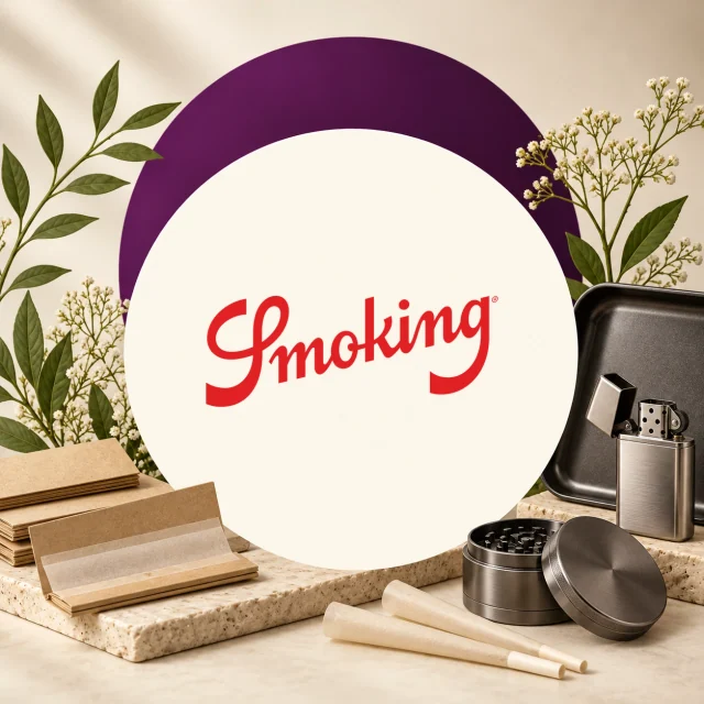 Logotipo rojo de Smoking en un círculo crema, rodeado de papeles de liar, conos, un grinder abierto y un encendedor metálico. Logotipo rojo de Smoking en un círculo crema, rodeado de papeles de liar, conos, un grinder abierto y un encendedor metálico.