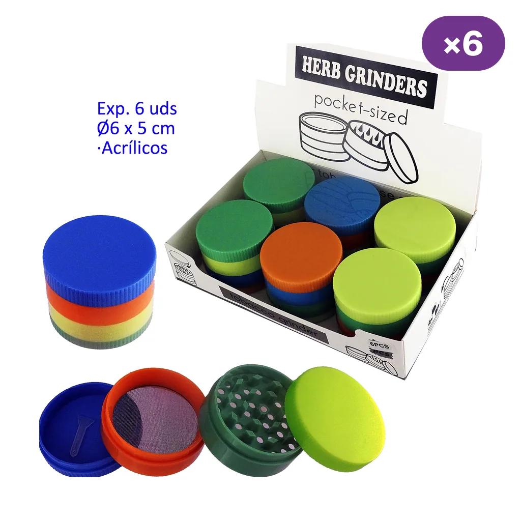 Grinders acrílicos de varios colores en expositor, con una unidad montada y otra desmontada que muestra dientes, malla y compartimento inferior.