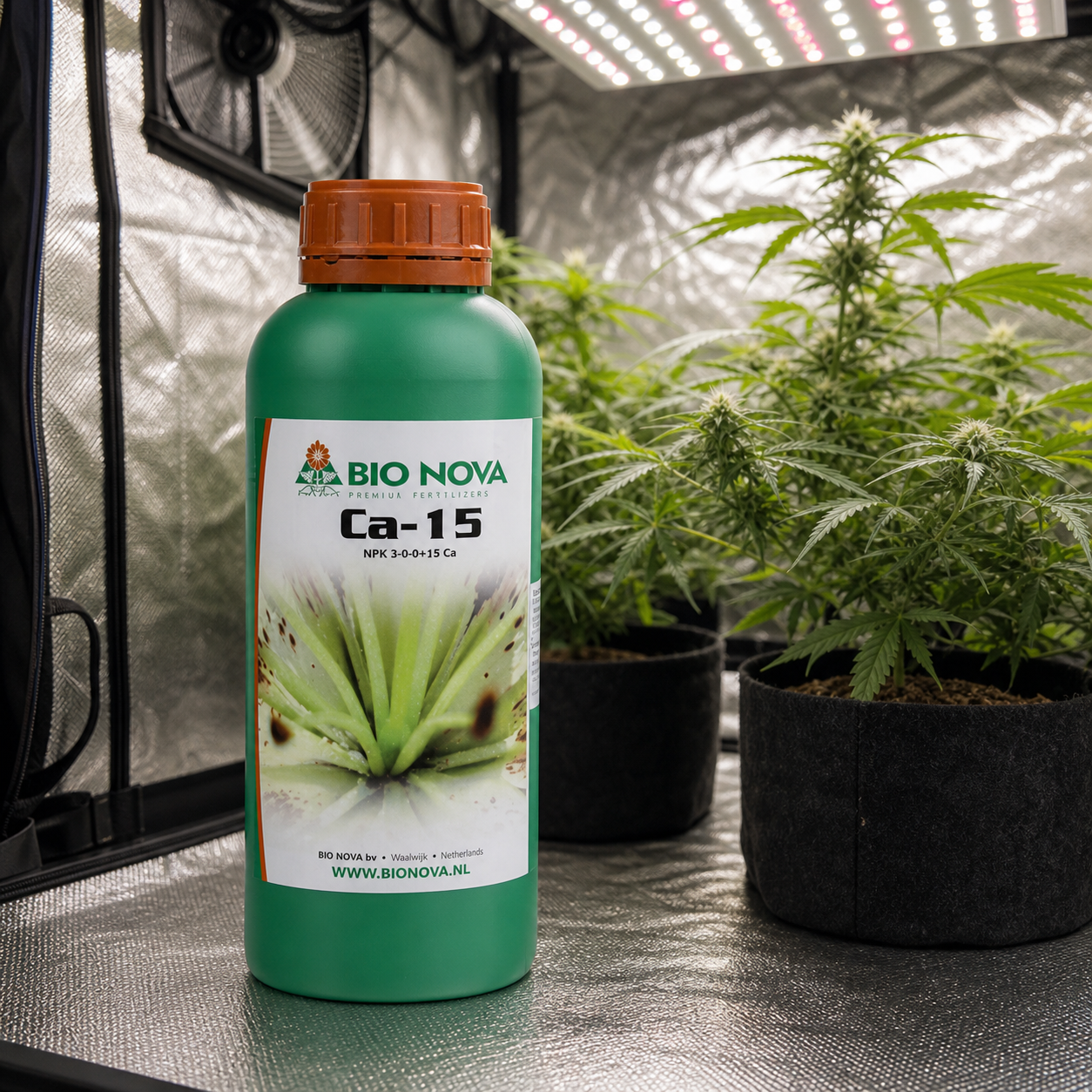 Botella verde de Bio Nova Ca-15 con tapón naranja, ante plantas en macetas dentro de un armario de cultivo con panel LED.