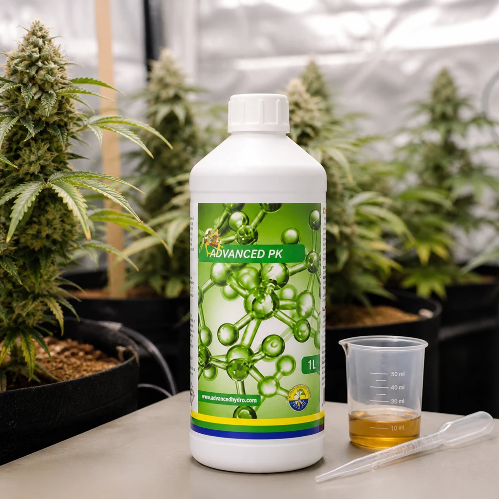 Botella de Advanced PK de 1 L junto a un vaso dosificador con líquido amarillo y una pipeta, con plantas en floración al fondo.