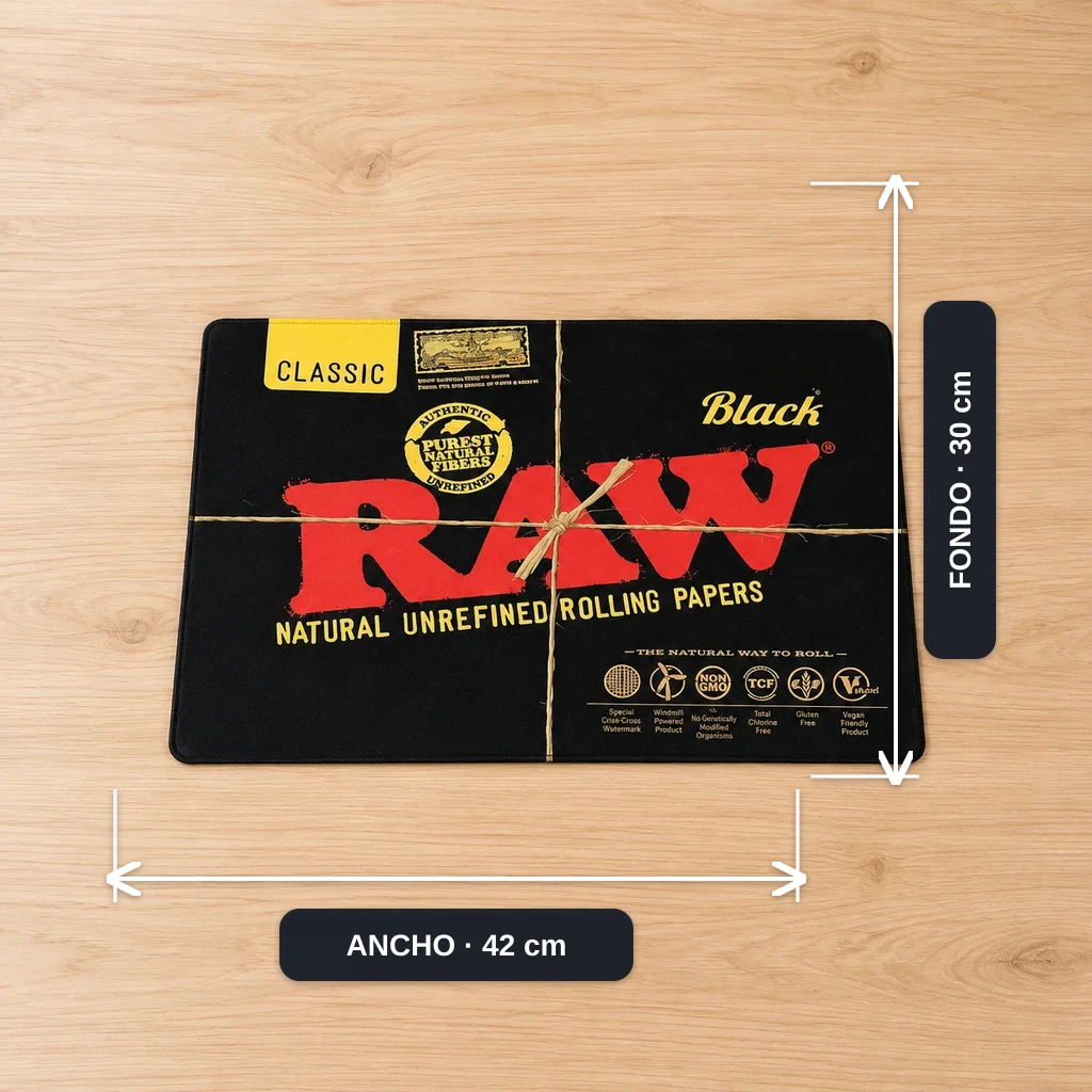 Alfombrilla RAW negra rectangular con gran logotipo rojo y letras amarillas, sobre una superficie de madera y rodeada de flechas de medida.