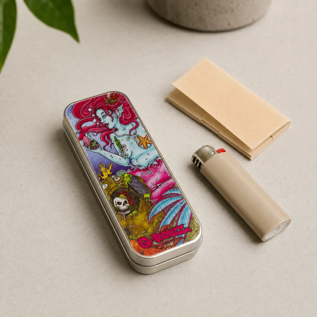 Caja rectangular cerrada con ilustración de una sirena de pelo rojo, junto a un mechero beige y papeles de liar sobre una mesa.
