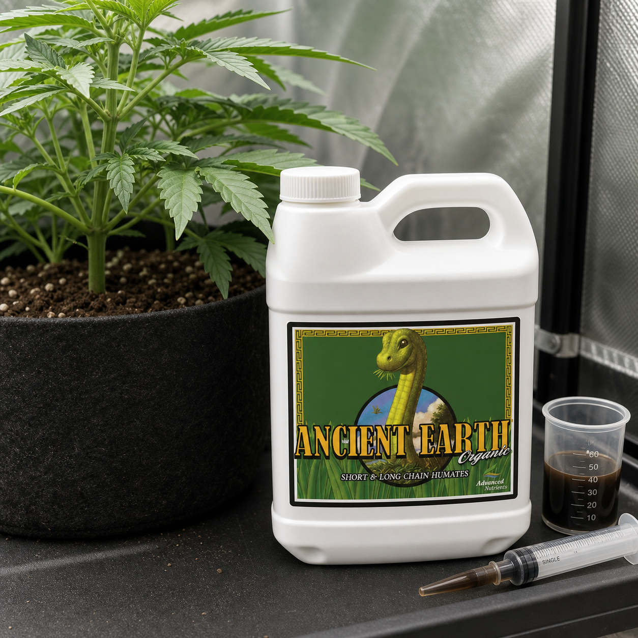 Garrafa blanca de Ancient Earth Organic junto a una planta en maceta, un vaso graduado con líquido oscuro y una jeringa. Garrafa blanca de Ancient Earth Organic junto a una planta en maceta, un vaso graduado con líquido oscuro y una jeringa.