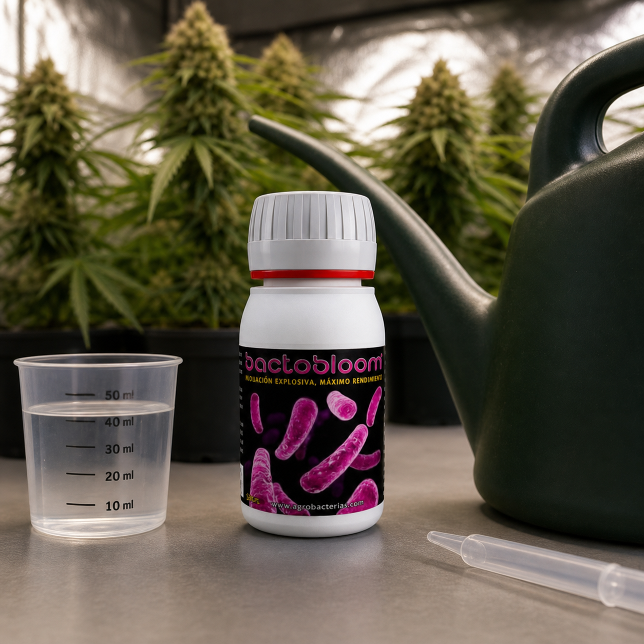 Bote de Bactobloom con etiqueta negra y rosa, junto a un vaso graduado, una pipeta y una regadera, con plantas en floración al fondo.