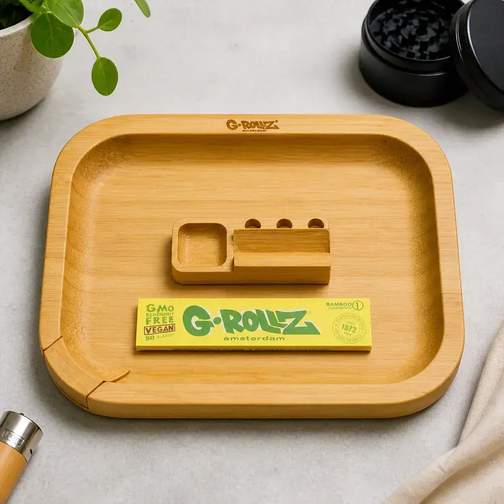 Bandeja de liar G-Rollz de bambú con bordes elevados, un soporte con compartimentos y un librillo amarillo de papel en su interior.