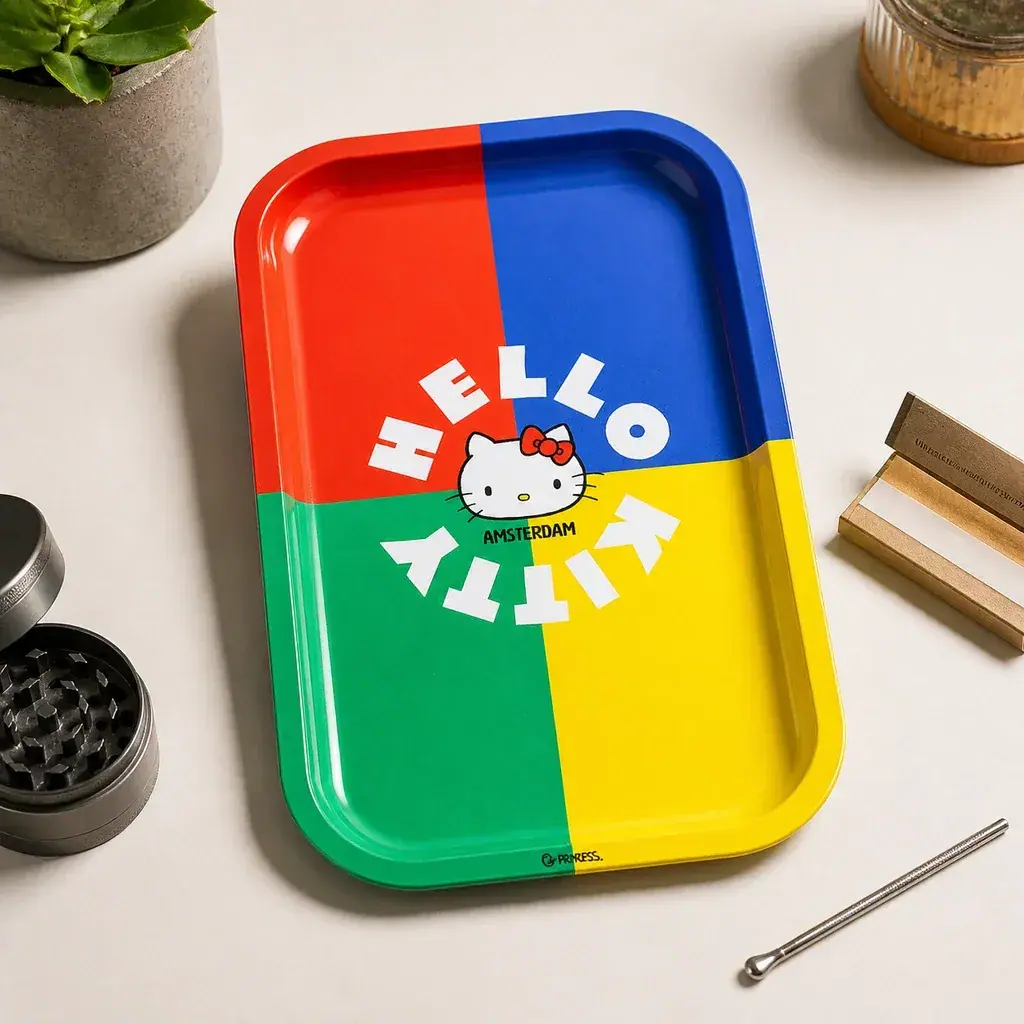 Bandeja de liar Hello Kitty con zonas roja, azul, verde y amarilla, junto a un grinder y papel de liar sobre una mesa. Bandeja de liar Hello Kitty con zonas roja, azul, verde y amarilla, junto a un grinder y papel de liar sobre una mesa.