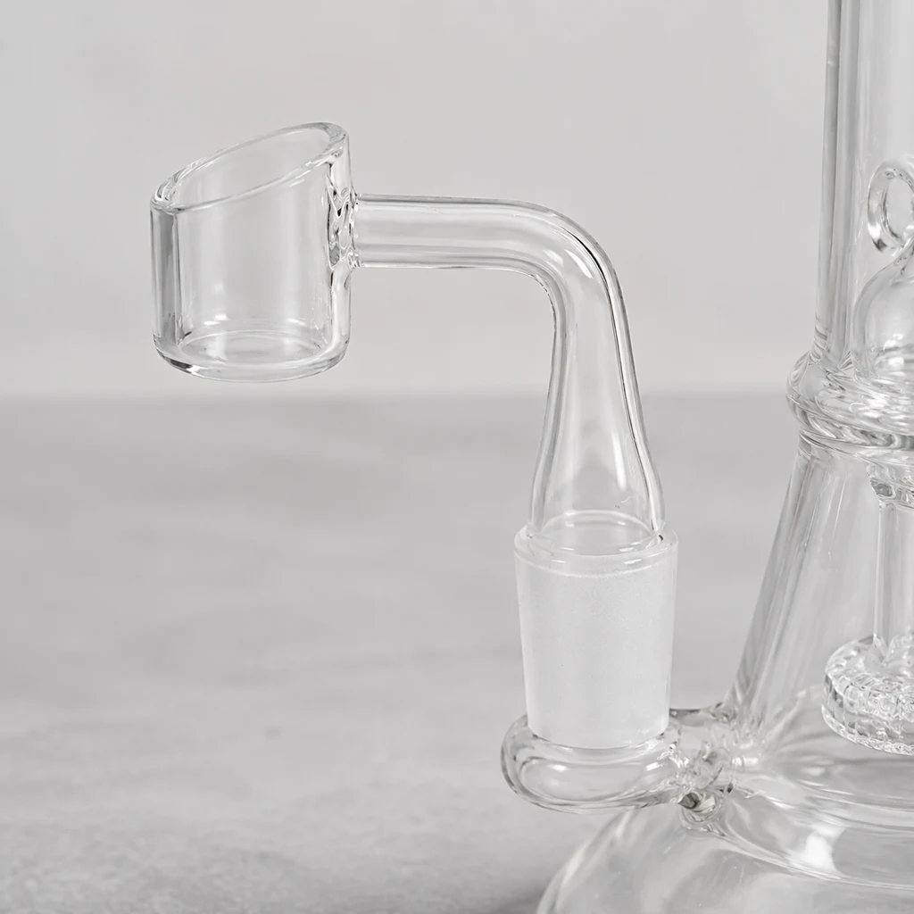 Detalle de un banger transparente de recipiente cilíndrico y brazo curvado, acoplado a la junta esmerilada de una pipa de agua.