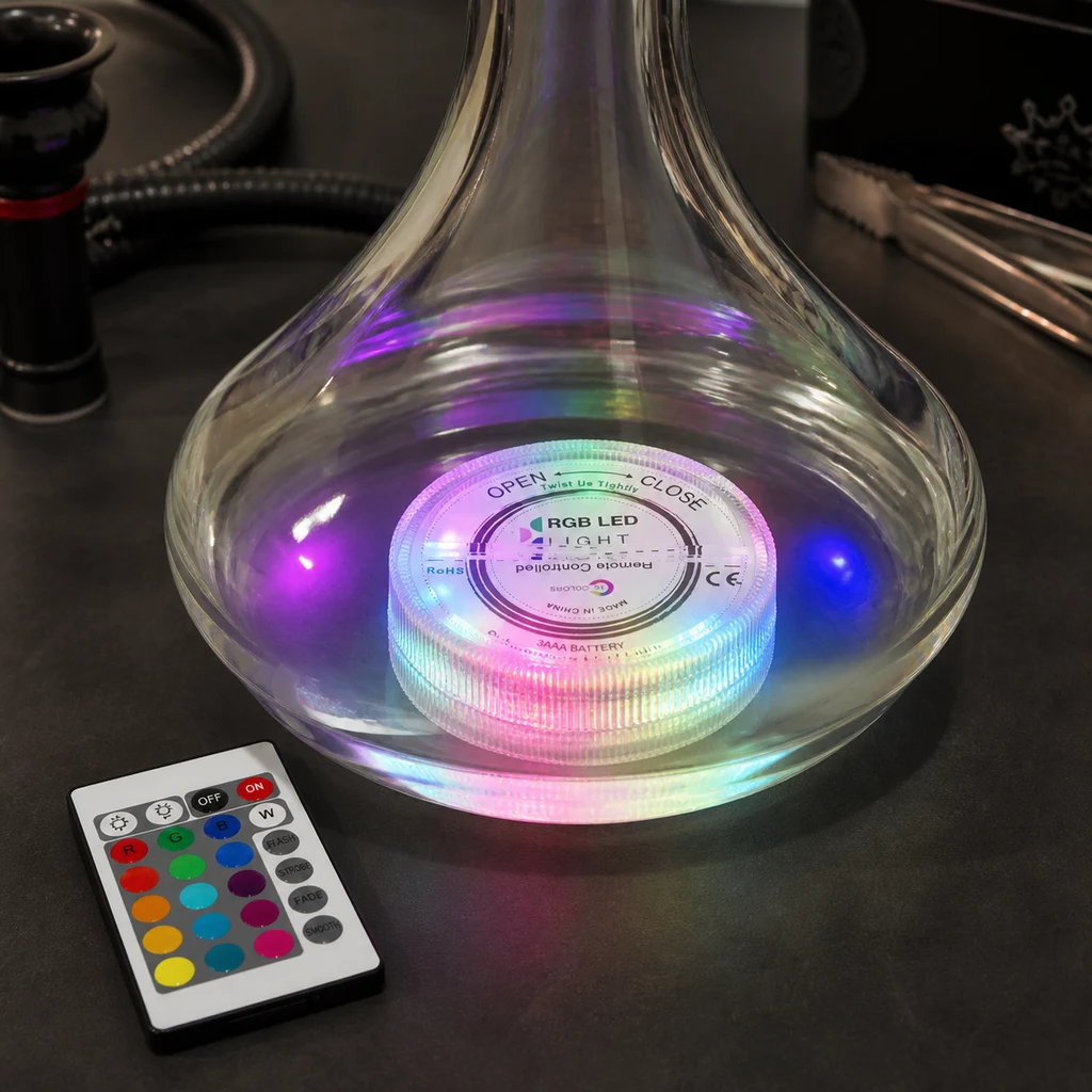 Base LED RGB con luces multicolores dentro del recipiente transparente de una cachimba, junto a un mando de botones de colores.